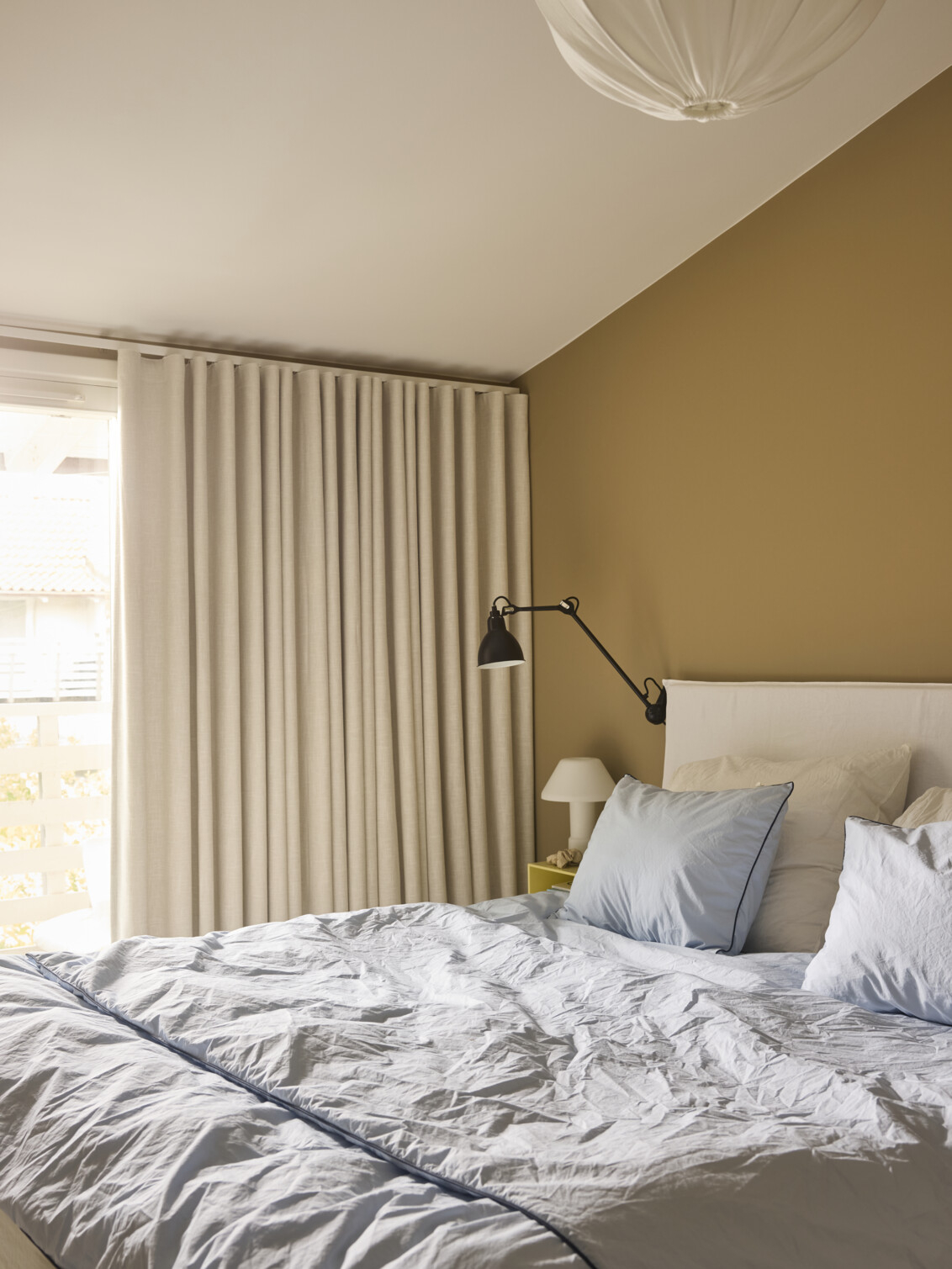 Bedroom with beige walls and a bed with light blue bedding.