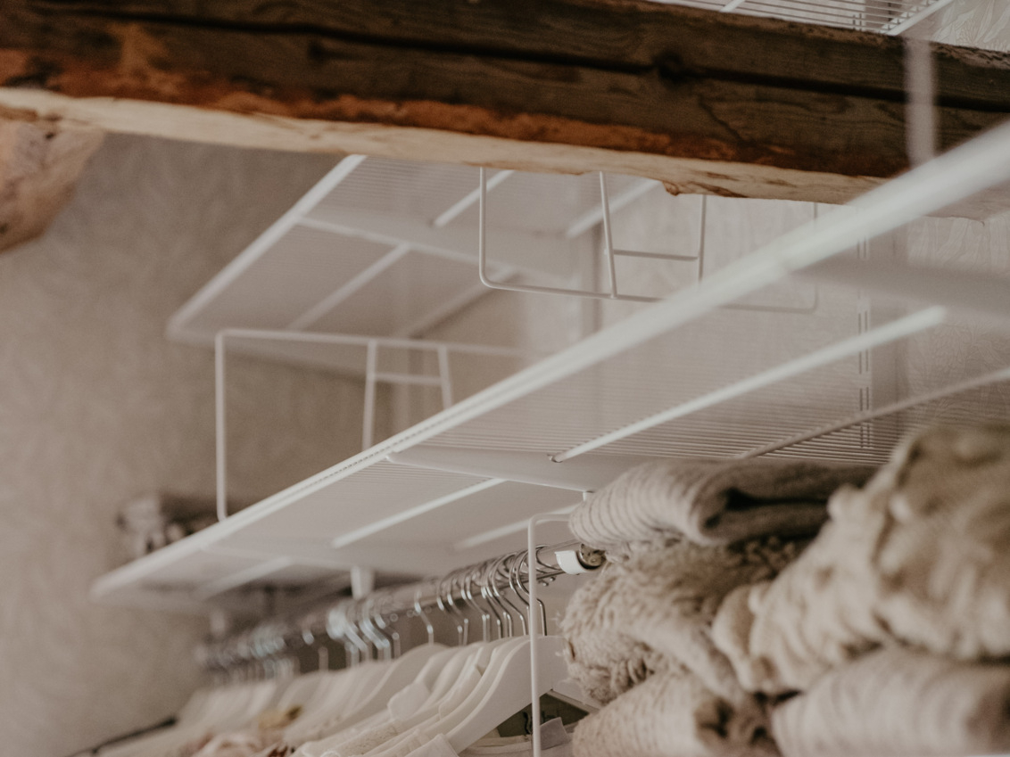 Ullakko kattopalkeilla, joissa on valkoinen Classic by Elfa -säilytyskaluste.