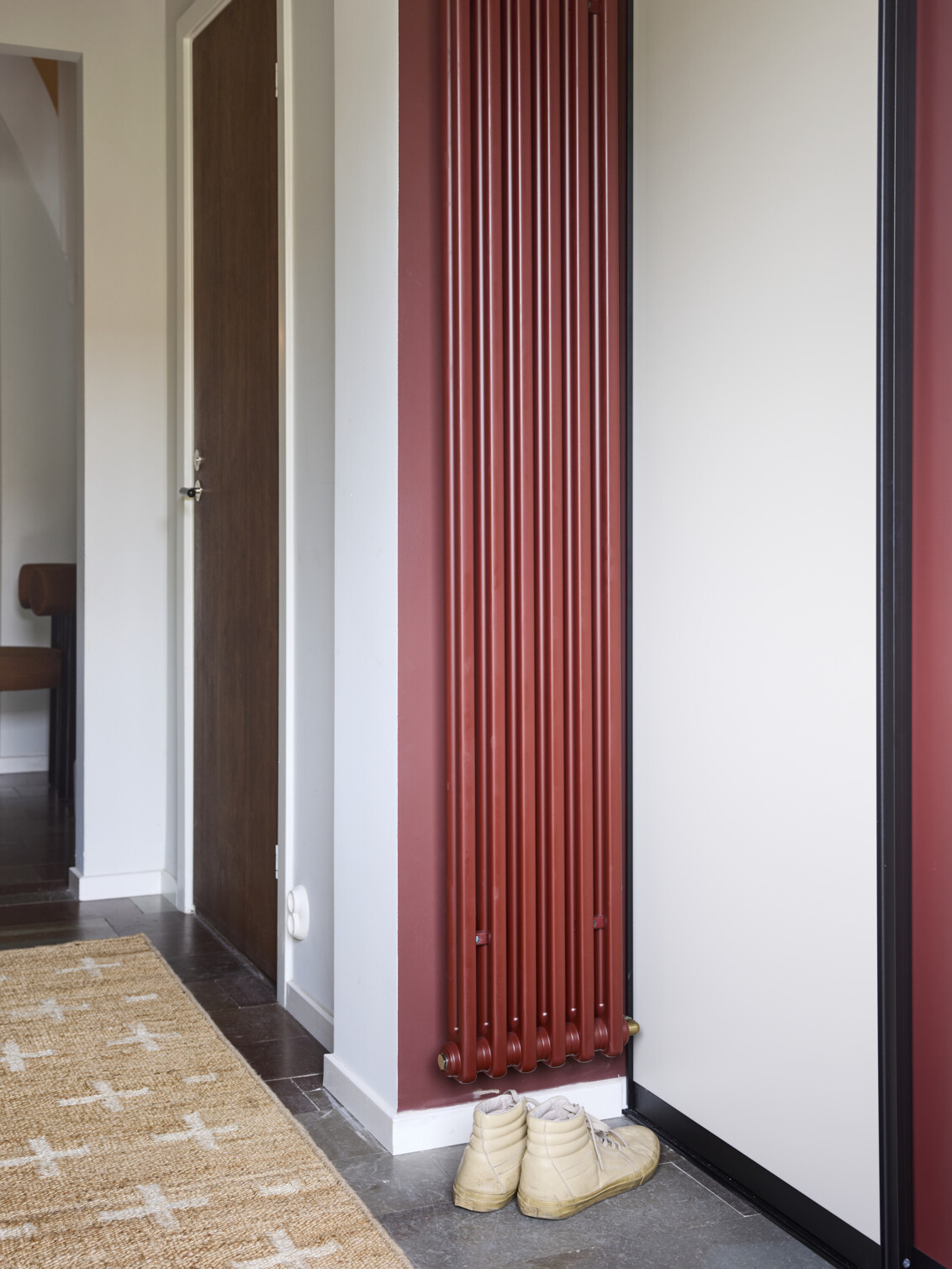 Hallway with walls and radiators in burgundy and a wardrobe from Elfa with the Vista sliding doors.