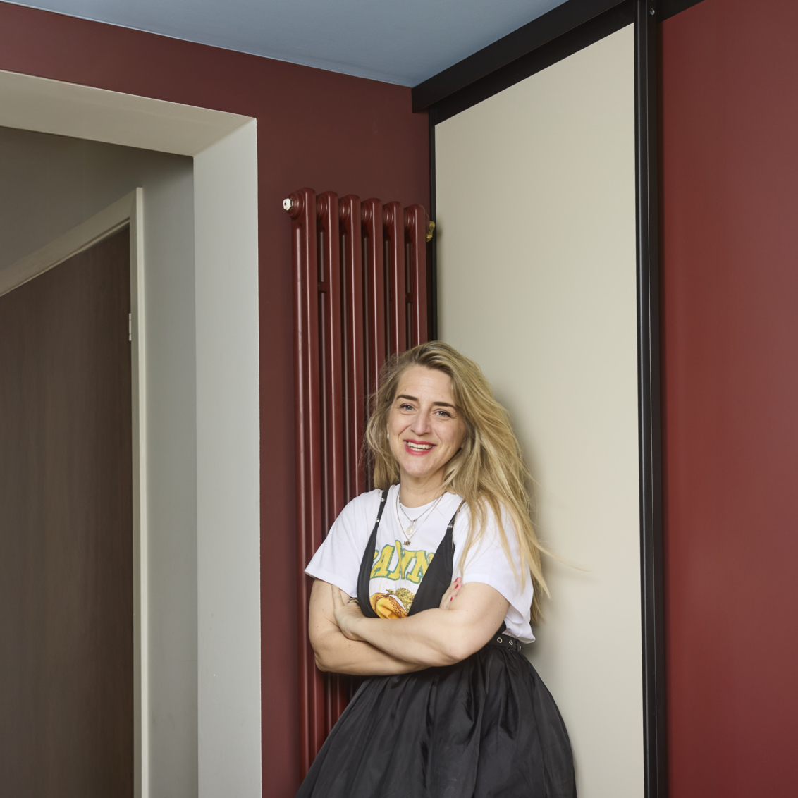 Caroline stands in the hallway in front of a wardrobe with sliding doors from Elfa.