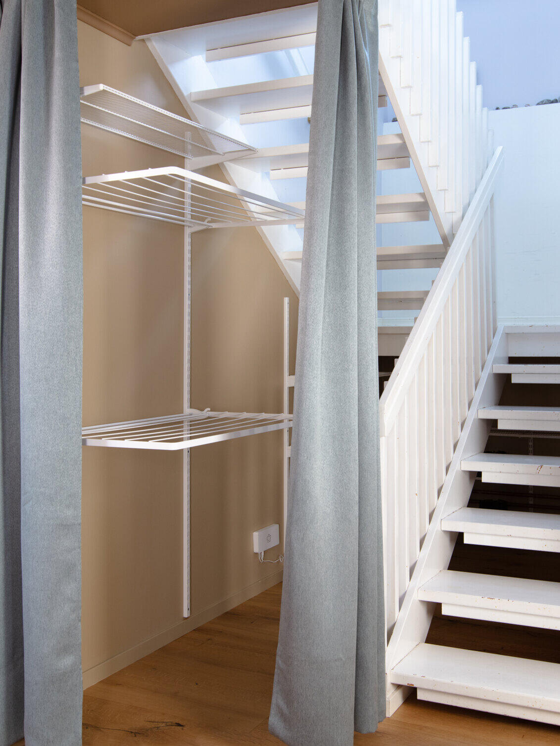 Området under trappen der det henger tørkehyller fra Elfa.