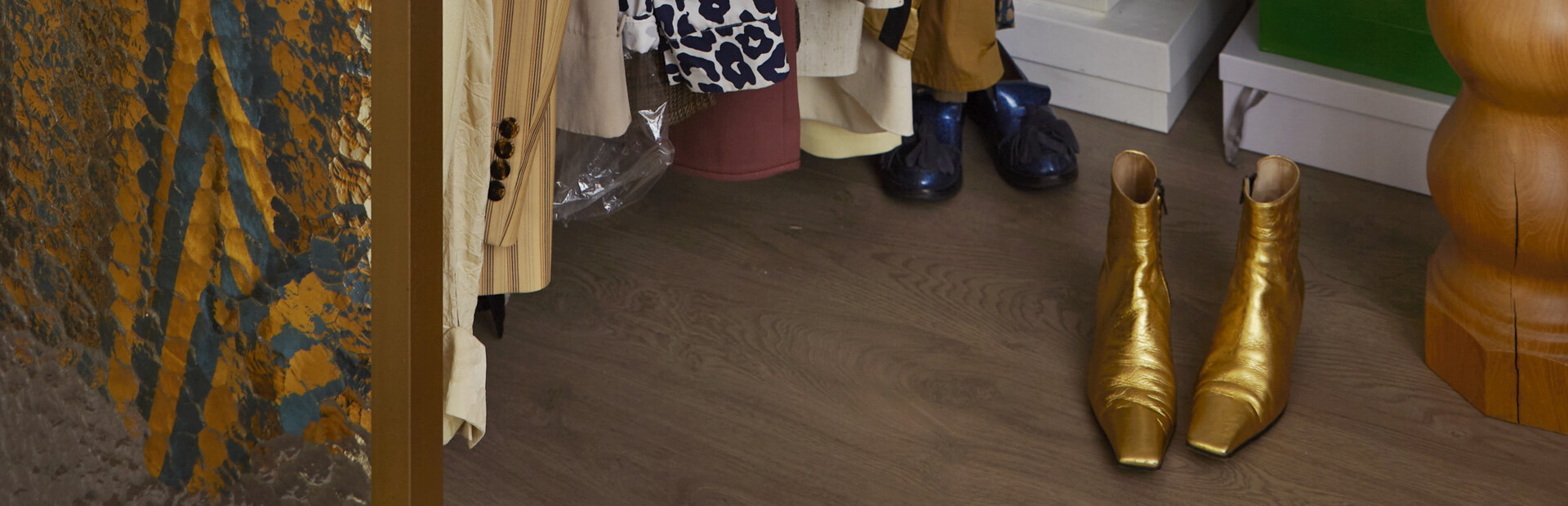 A pair of golden shoes standing on the floor in front of a wardrobe.