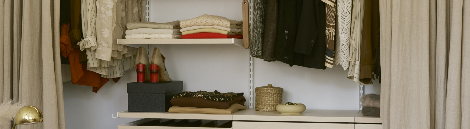 Clothing and accessories in a Classic by Elfa wardrobe in white and birch.