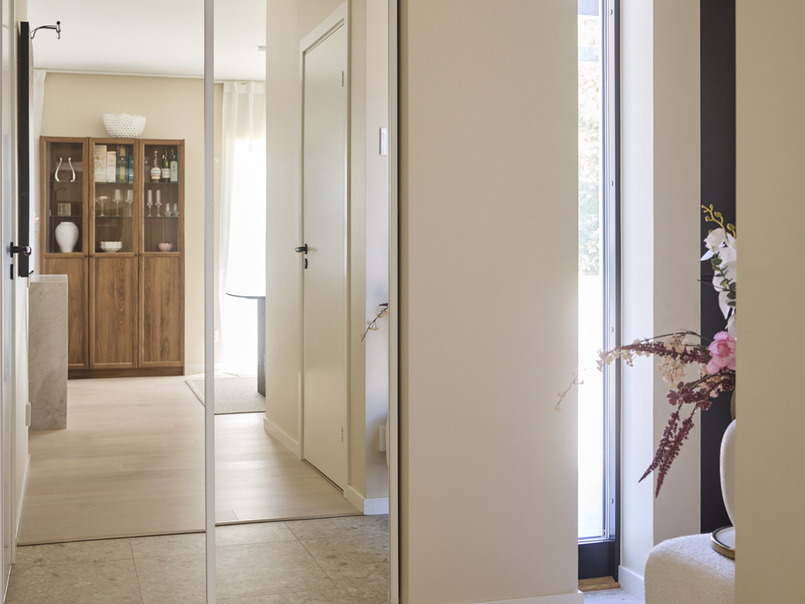 Hallway with wardrobe with sliding doors from Elfa where a chest of drawers is visible in the mirror image.