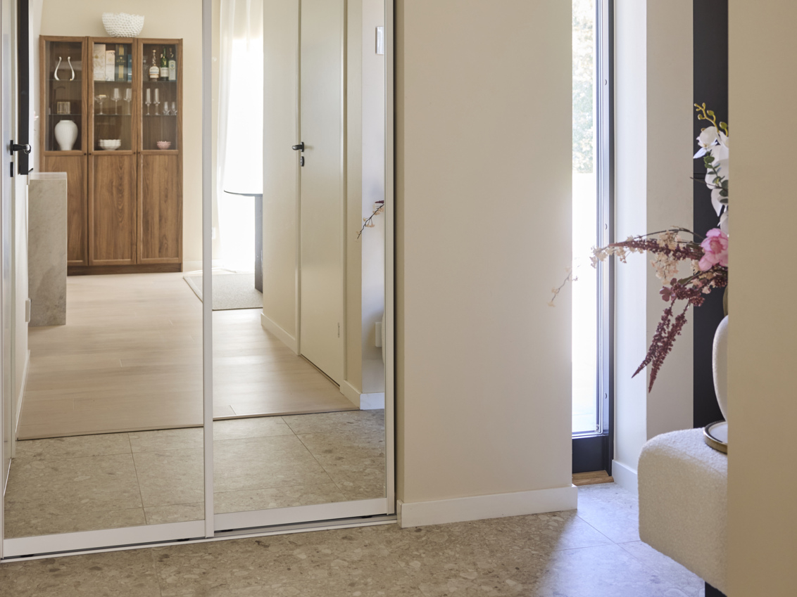 Eteinen, jossa on vaatekaappi, jossa on Elfan liukuovet ja peilikuvassa lipasto.