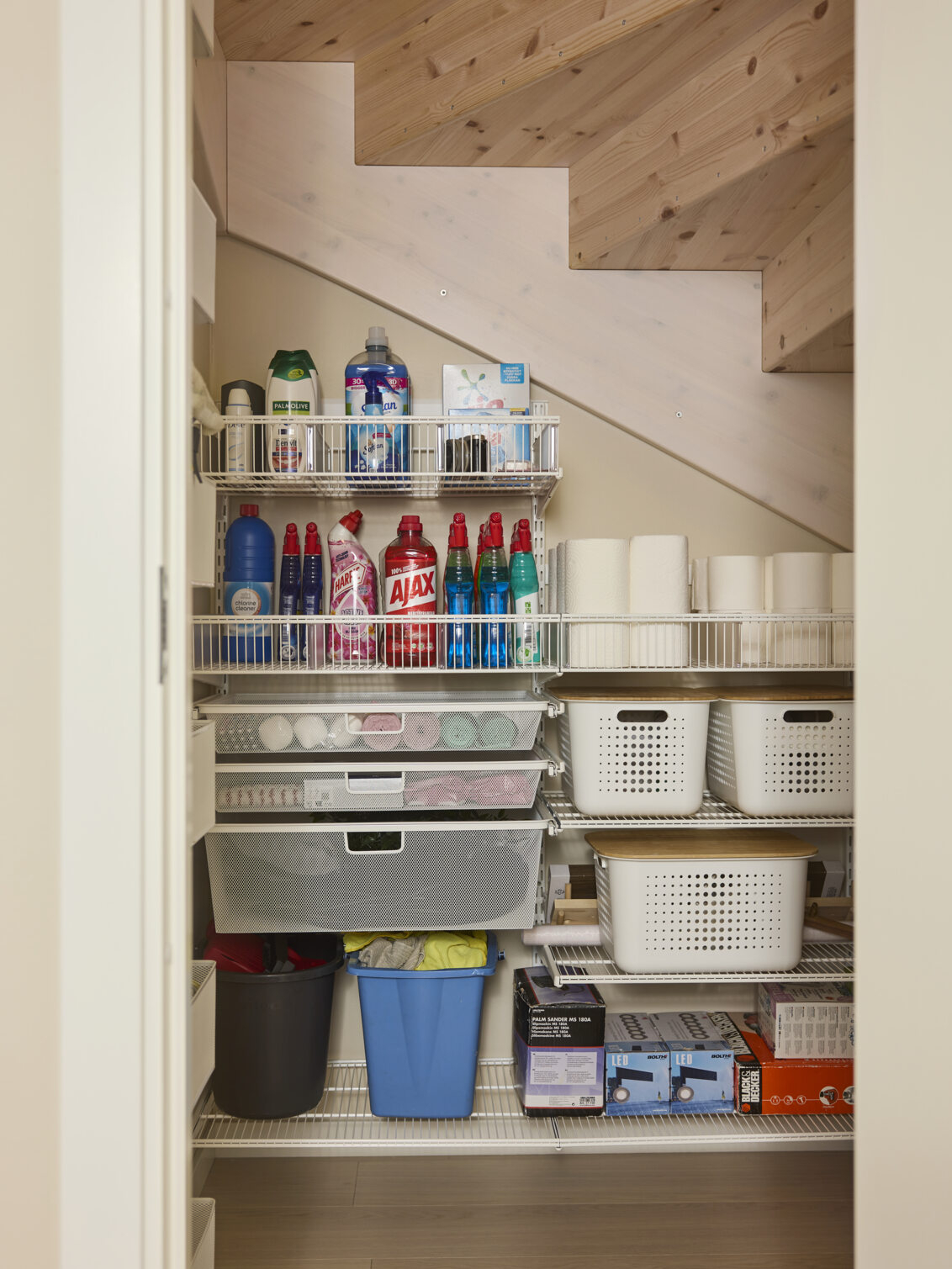 Classic by Elfa wire shelves in white under a staircase where cleaning items are stored.