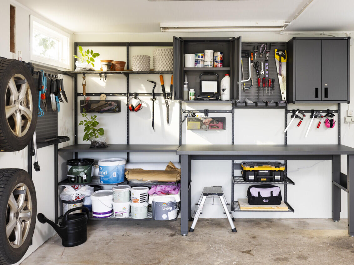 Garage with Garage+ storage from Elfa with wire shelves, storage track, cabinet and workbench for storing tools.