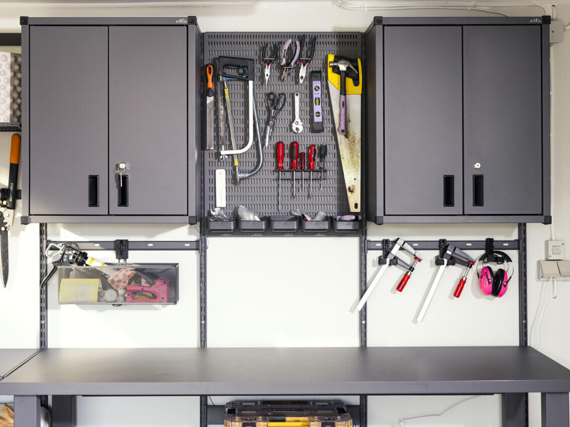 Garage with Garage+ storage from Elfa with cabinet, storage board for hanging tools and a workbench. 