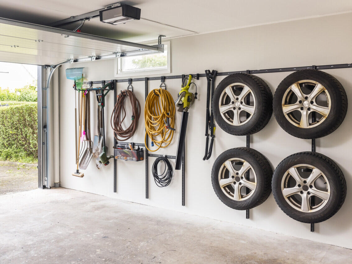Garage with Garage+ storage track from Elfa used for hanging car tyres, hoses and garden tools.