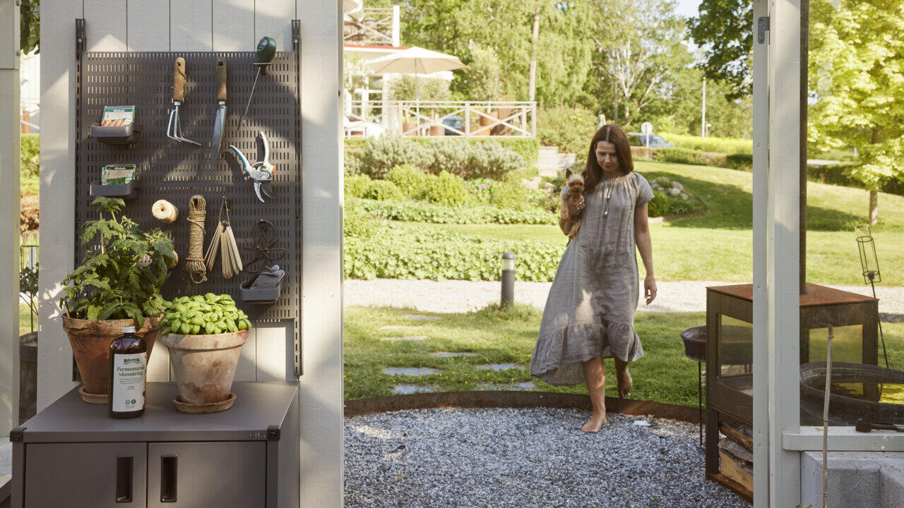 Carin on her way into the greenhouse, where there is a Garage+ peg board from Elfa with gardening tools.