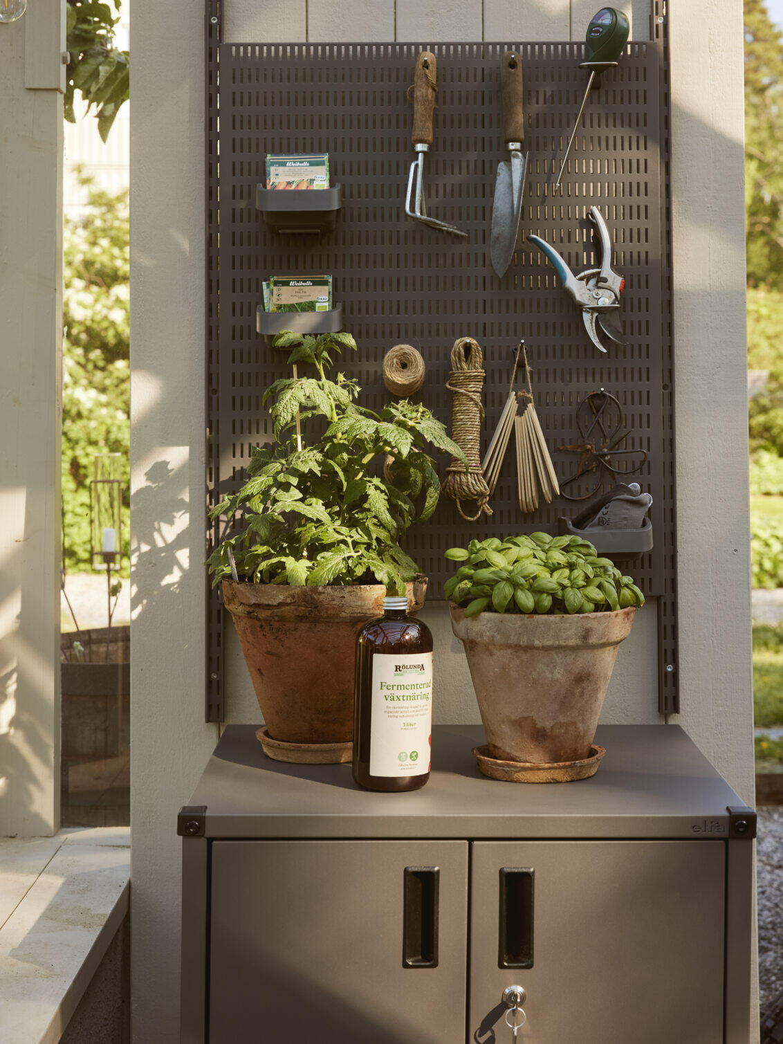 Garage+ peg board and lower cabinet from Elfa for storing gardening tools.