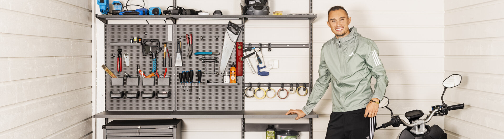 Thobias Montler stands in a garage with storage from Garage+ by Elfa where tools hang.
