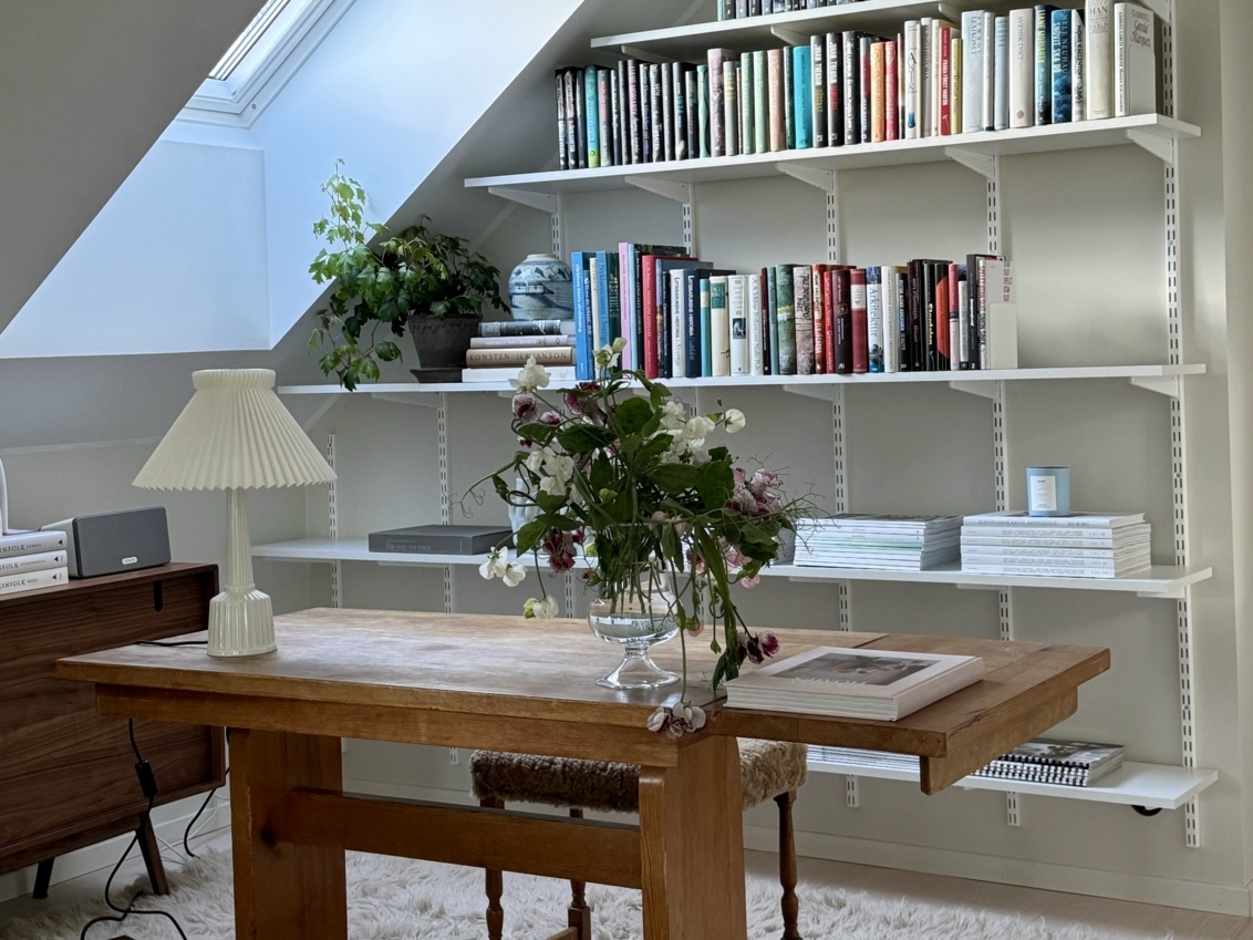 Domowe biuro z biurkiem i regałem Sparring Elfa pod skosem.