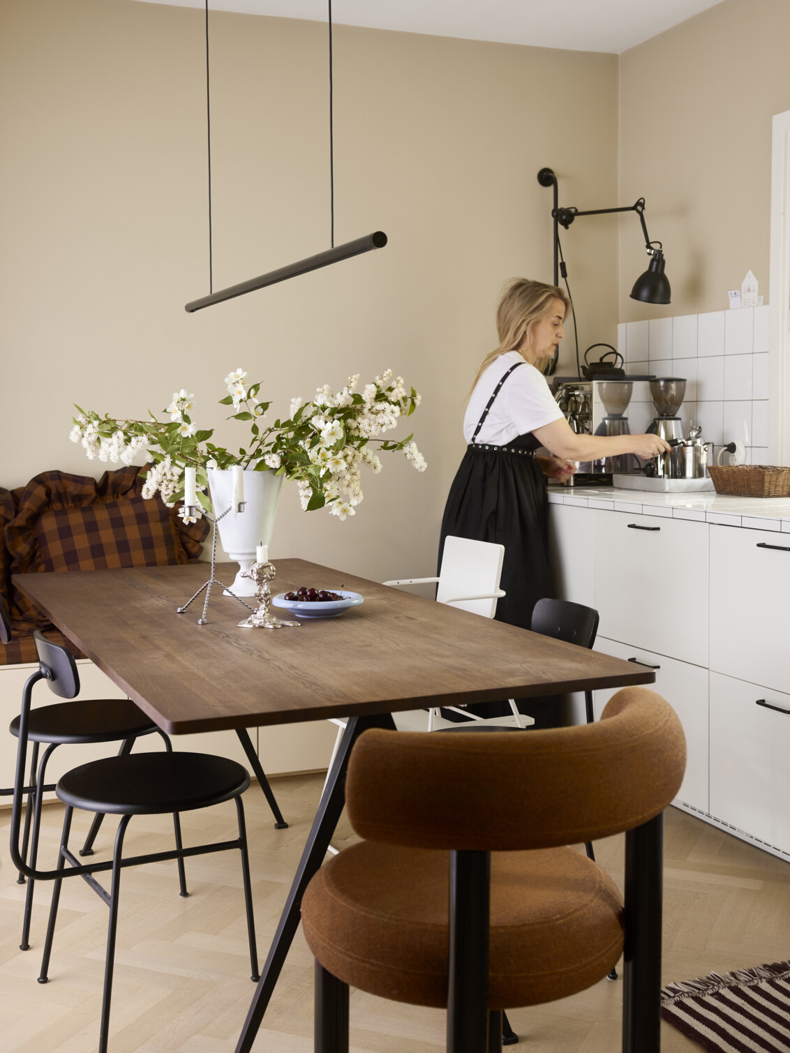 Caroline stands in a kitchen with beige walls and a dining table with a vase with white flowers.