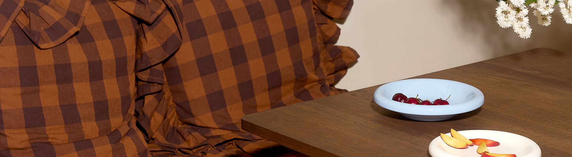 Checked pillows in brown at a table with small plates with fruit and berries.