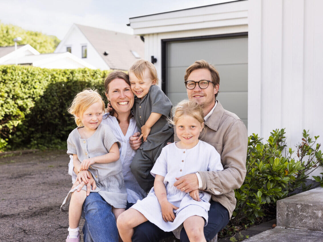 Gustav and Annika sit with the children in front of the closed garage door. 