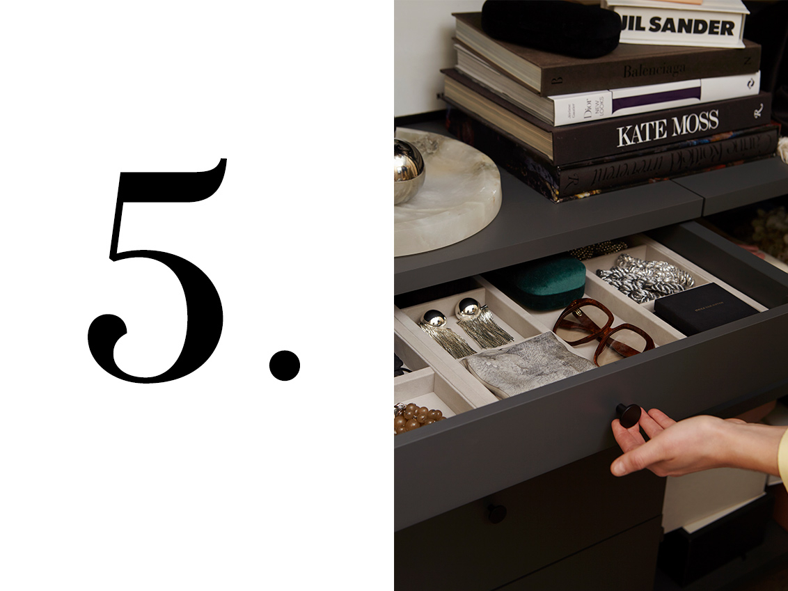 A hand pulls out a grey Décor+ by Elfa drawer containing accessory tray filled with jewellery and a pair of glasses.