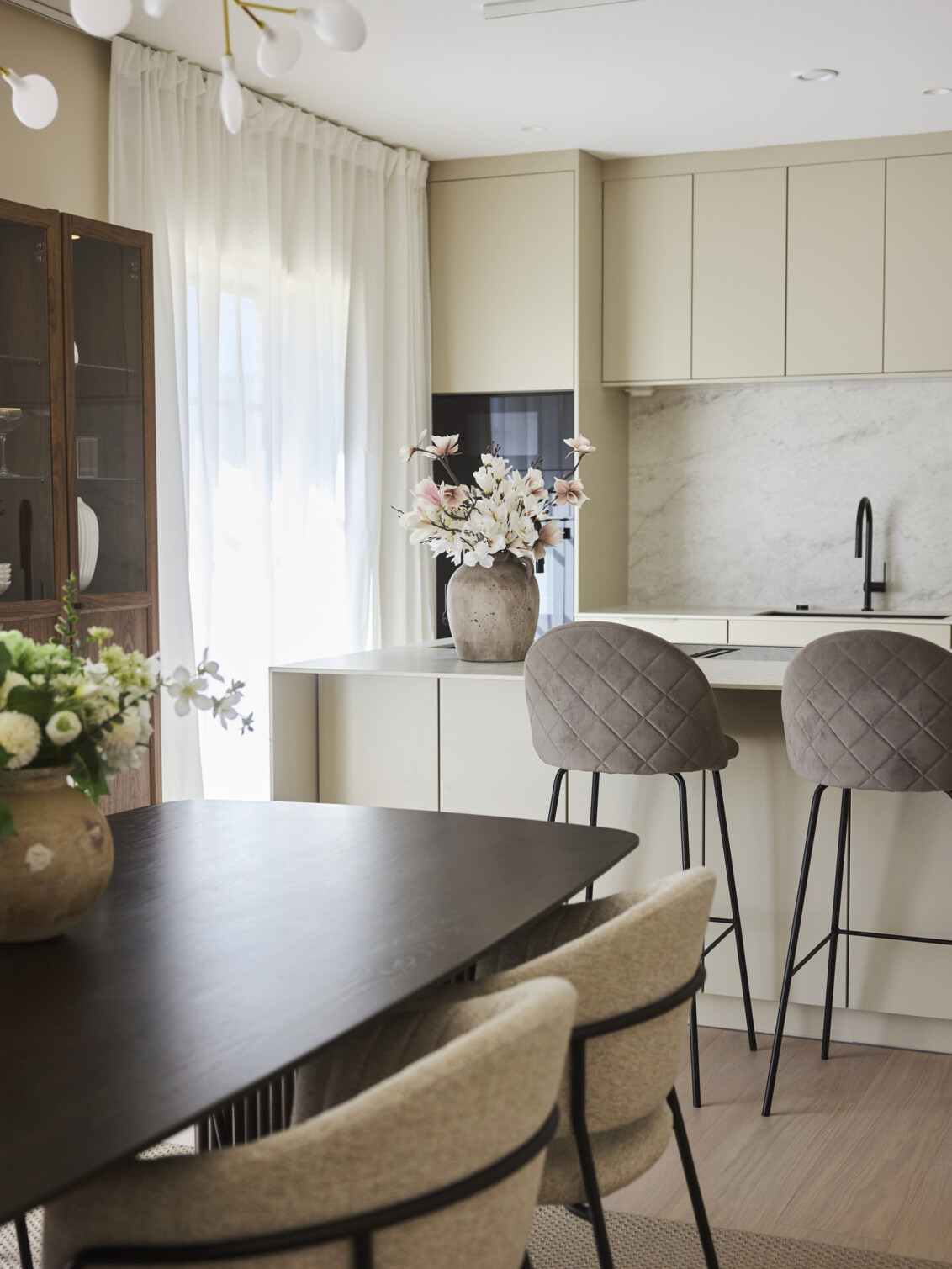 Kitchen in light tones with a kitchen table in dark wood.