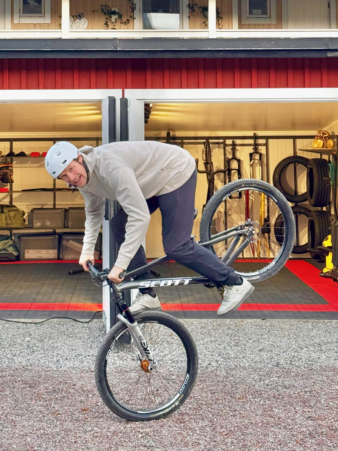 Martin Söderström tekee tempun polkupyörällään autotallinsa ulkopuolella; tallissa Garage+ by Elfa -säilytysratkaisu.