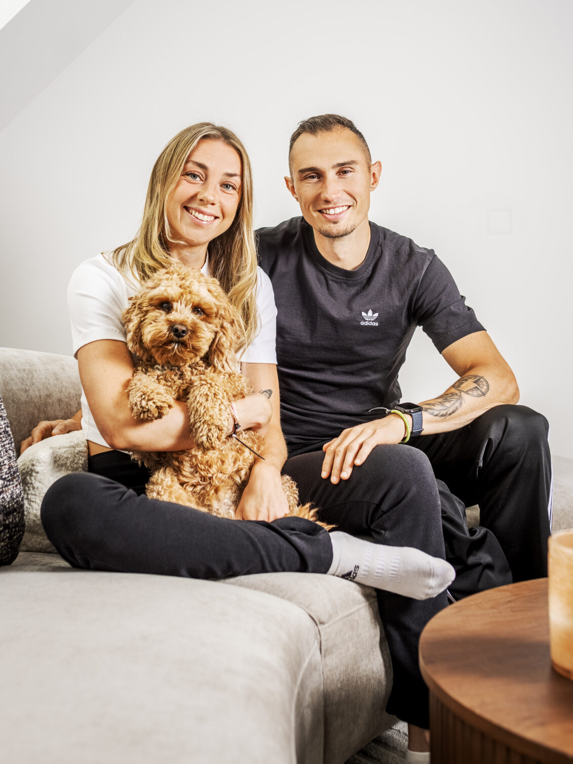 Thobias and Lisa are sitting on a sofa with their dog.