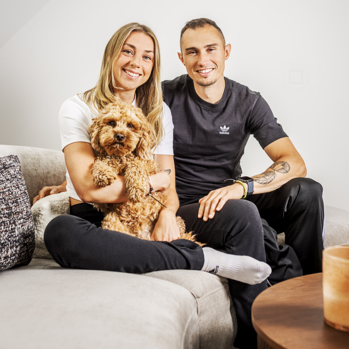 Thobias and Lisa are sitting on a sofa with their dog.