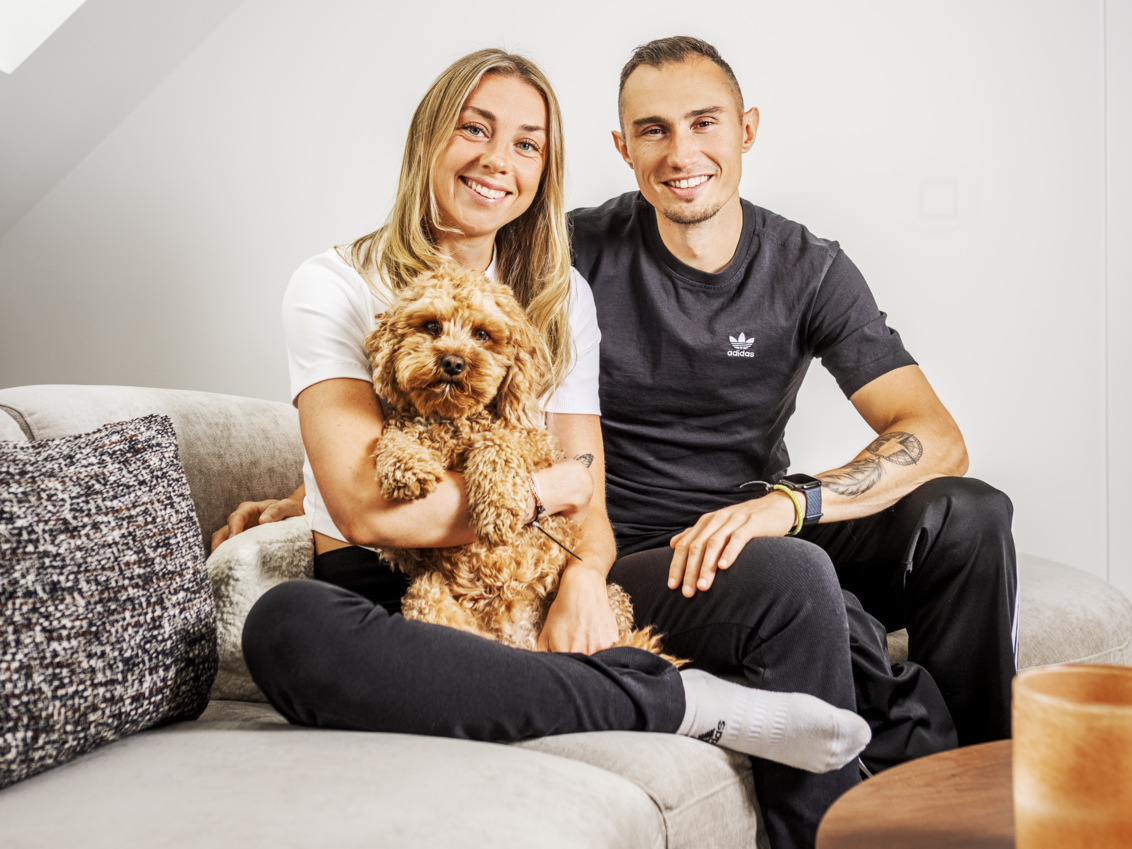 Thobias and Lisa are sitting on a sofa with their dog.