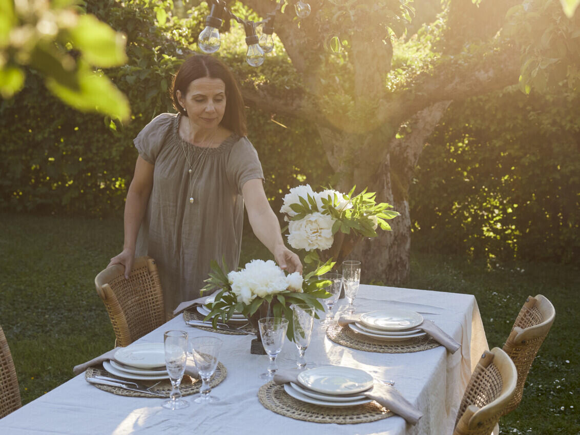 Carin sets a table with white flowers in the vases.