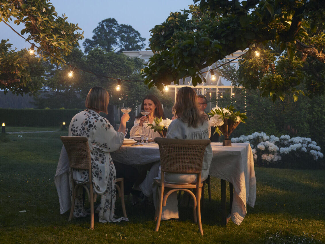 Four people having a toast in the garden at dusk.
