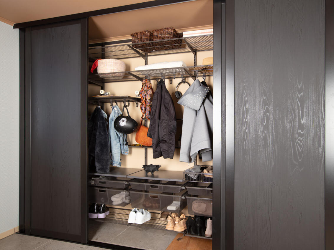 Eteinen, jossa on Elfan vaatekaappi, missä on ripustettuja ulkovaatteita, kenkiä sekä mustat Grace-liukuovet.