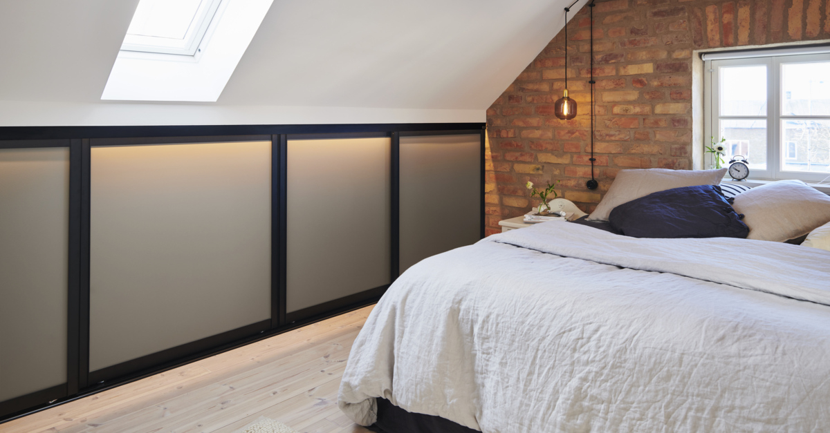 Makuuhuone, jossa on matala vaatekaappi, jossa on Elfan liukuovet vinokaton alla.