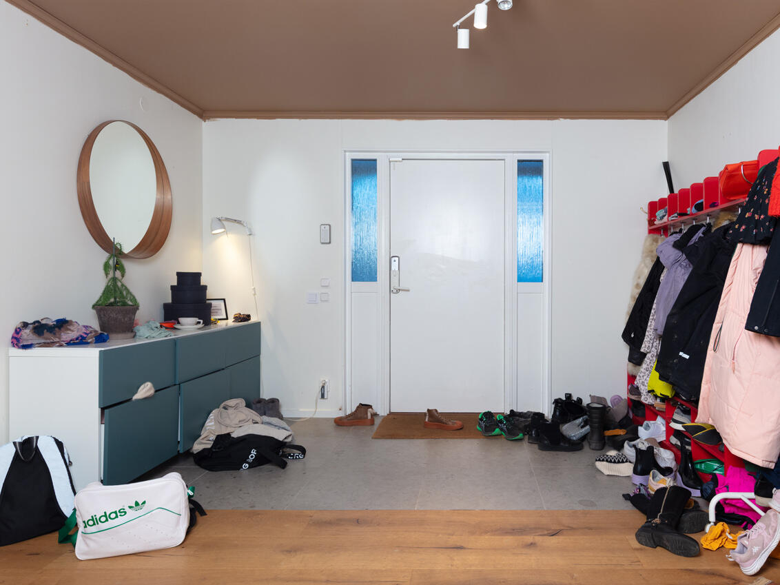 Gangen som den så ut før, med en rød barnehagehylle og en blå kommode.