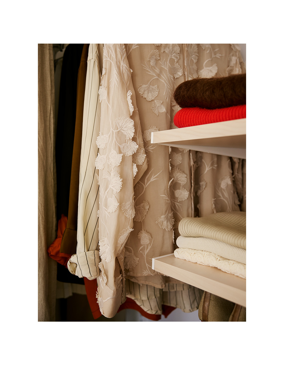 Hanging clothing in a Décor+ by Elfa wardrobe with shelves in birch.