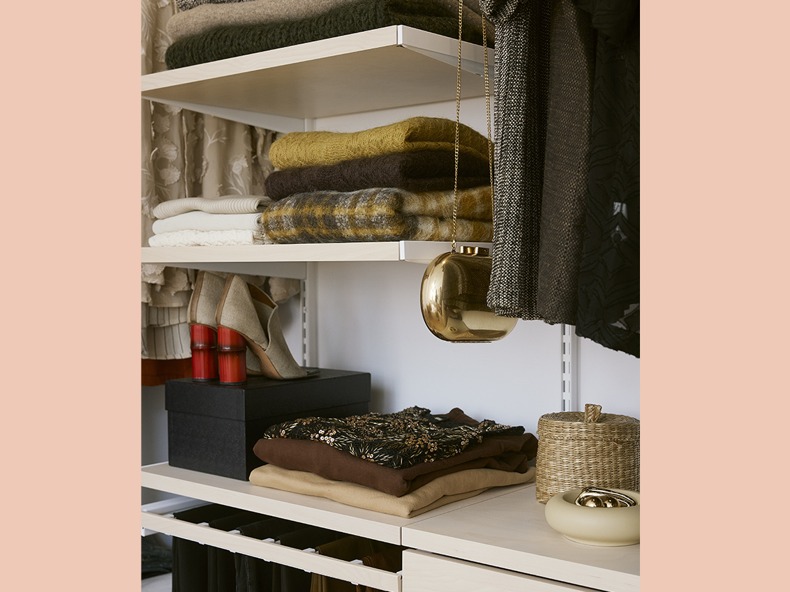 Clothing and accessories in a Décor+ by Elfa wardrobe in white and birch.