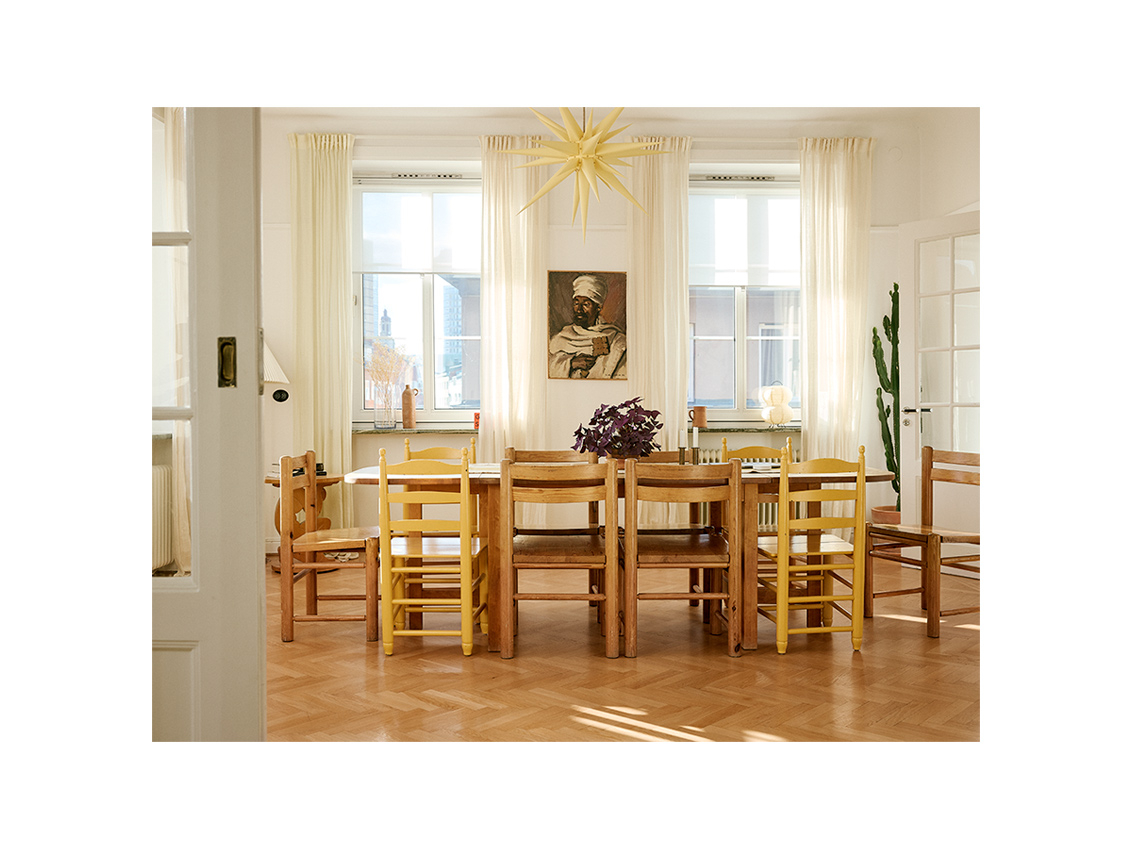 The dining room in Emma and Saif’s home, with tall windows and tables and chairs in solid wood.