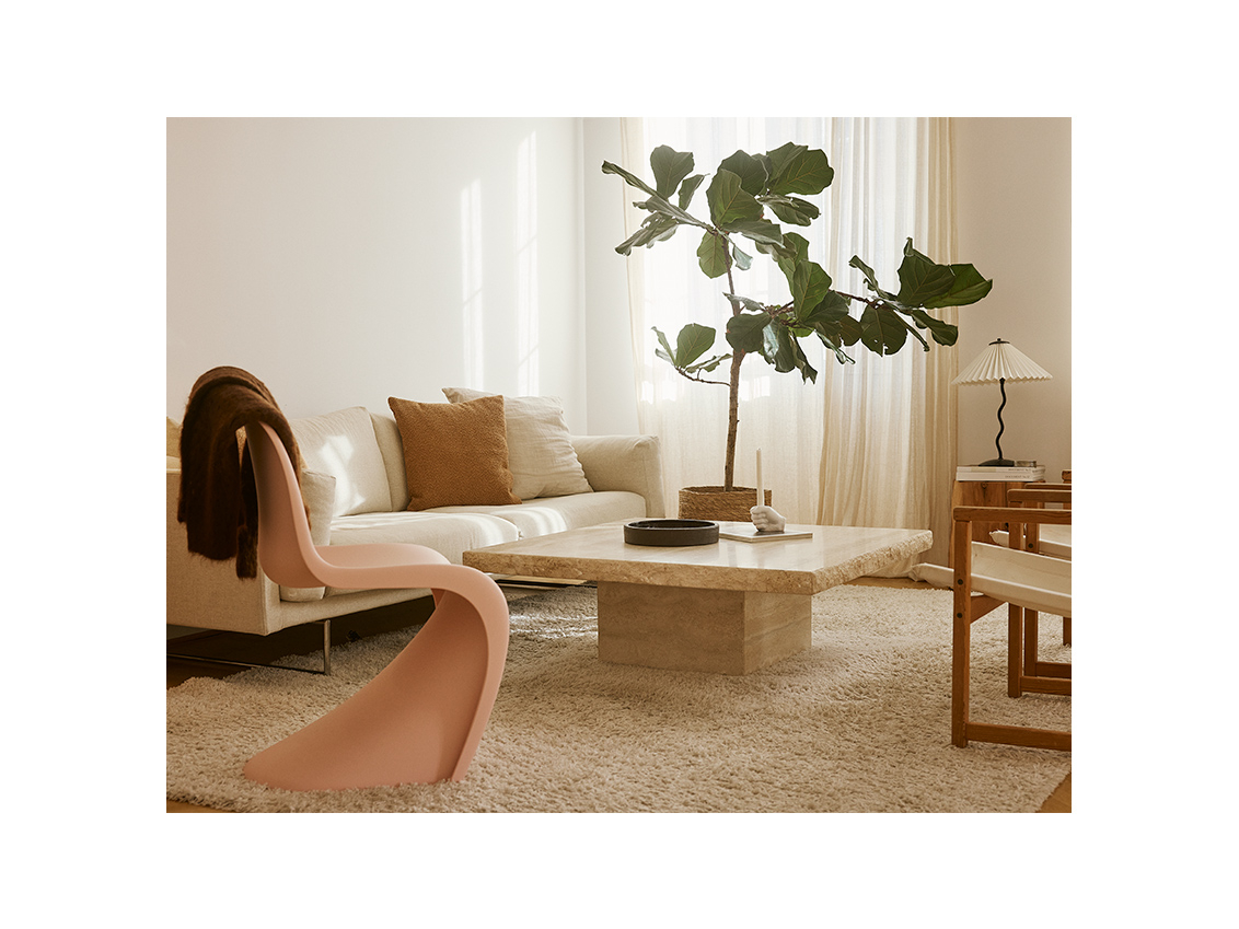 Living room with a white fabric sofa, stone coffee table and a pink plastic chair.