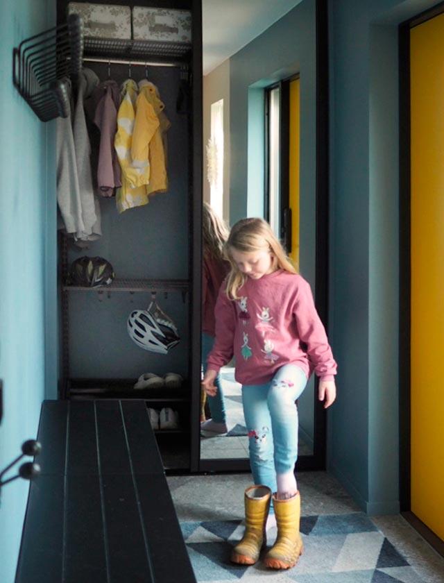 Vaatekaappi makuuhuoneessa peilitäytteellä. Lapsi laittaa kengät jalkaan