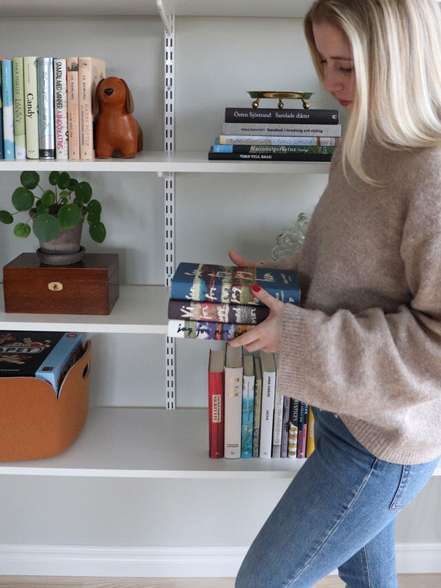 Kobieta stoi przed systemem regałów z książkami