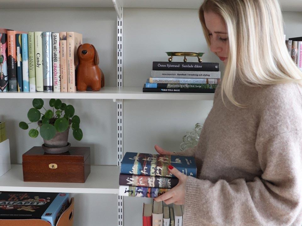 A woman stands in front of a shelving system with books