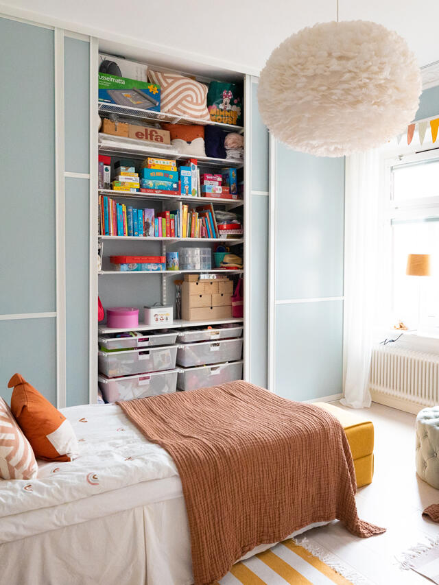Children's room with Classic by Elfa wardrobe, filled with children's clothes, games and toys, where the sliding doors are in light blue.