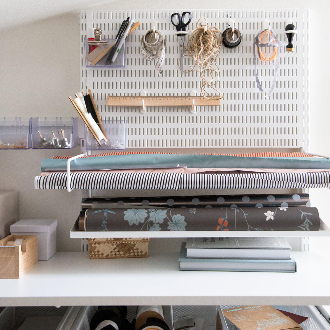 Cosas como papel de regalo, cinta adhesiva, cuerda, tijeras y papel de regalo en elfa Tablero de almacenamiento