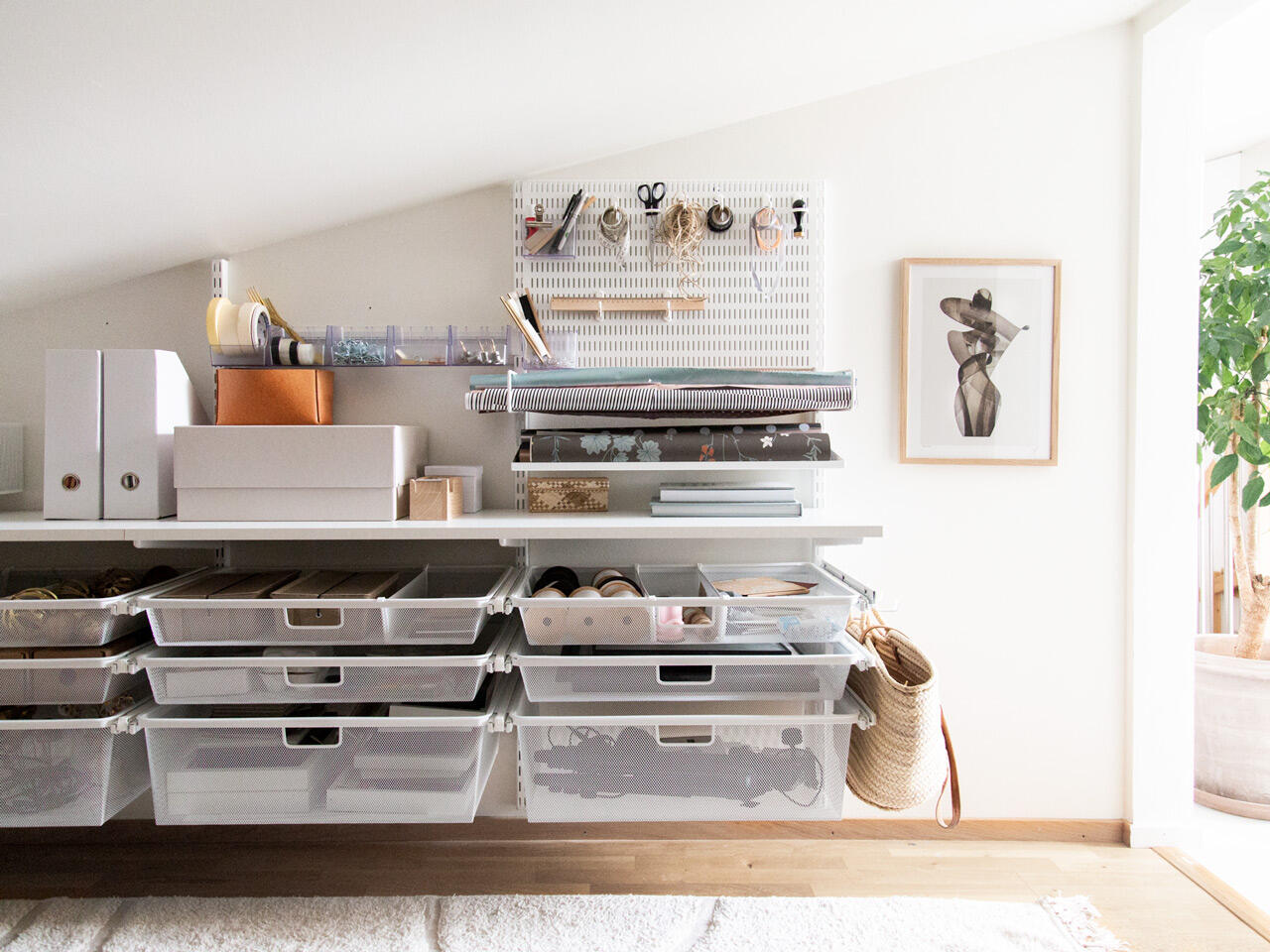 Estación de trabajo de hobby montada en la pared con el sistema Click-in de Elfa y almacenamiento inteligente con ganchos, cajas y bandejas