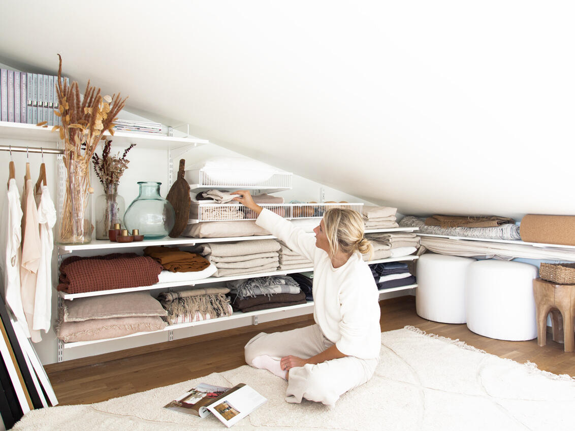 Una mujer se sienta en el suelo frente a un sistema de estanterías con almacenamiento de ropa