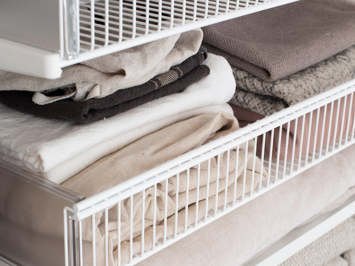 Toallas organizadas en la cesta de alambre Elfa para un almacenamiento inteligente y aireado