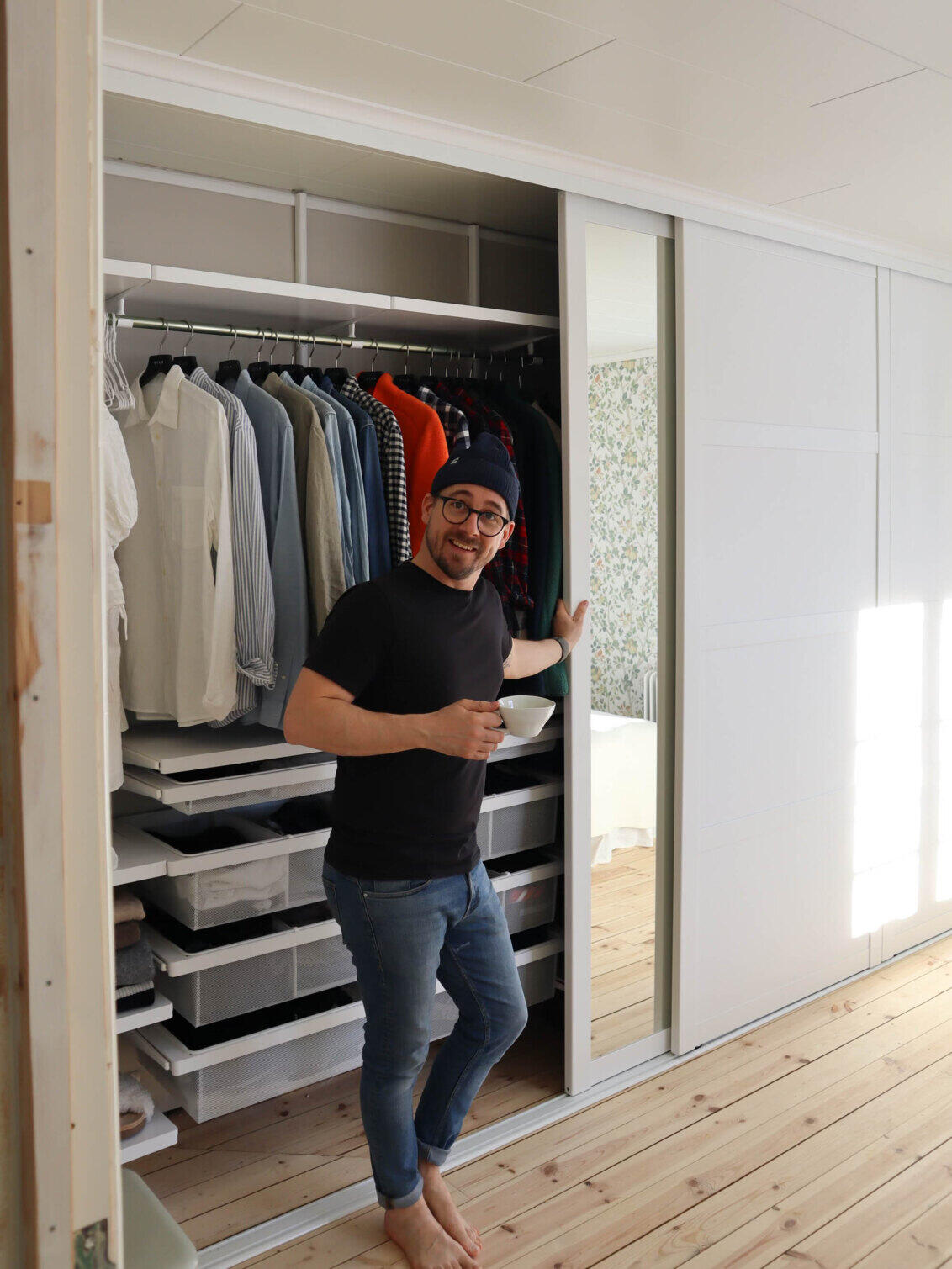 Mies seisoo liukuovikaappinsa edessä