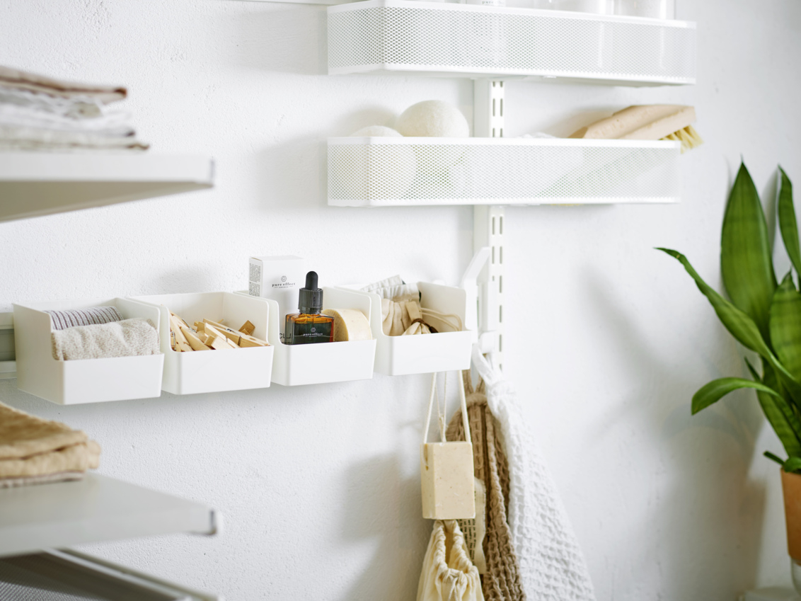 Laundry room with storage from Classic by Elfa with mesh baskets and white boxes with clothespins on a storage rail.