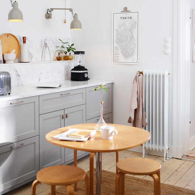Jasna kuchnia z szarymi szafkami, marmurowym blatem i drewnianymi podłogami w stylu skandynawskim