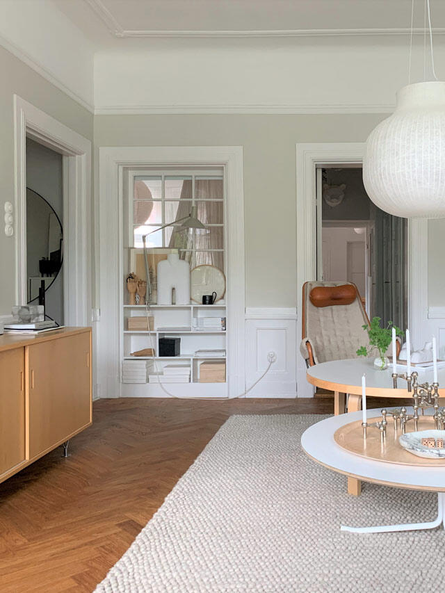 Jasny salon z drewnianą podłogą, półką na książki i okrągłym stolikiem kawowym w stylu skandynawskim