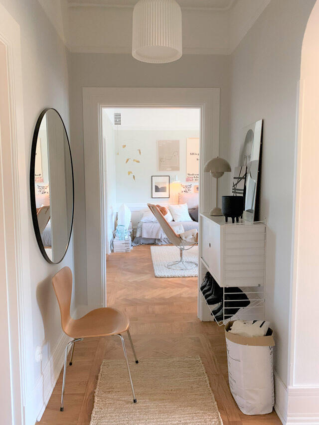 Białe rozwiązanie do przechowywania Elfa w przedpokoju z lustrem, krzesłem i koszem do przechowywania