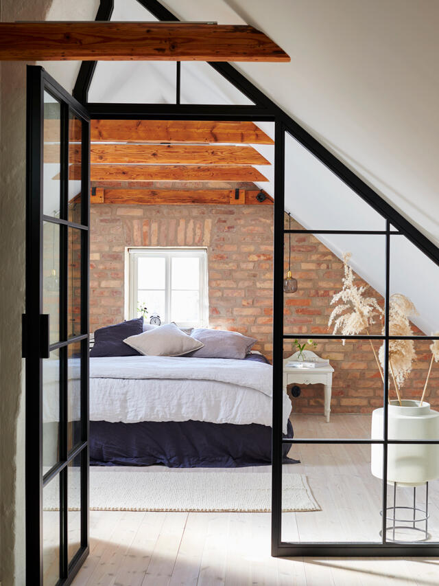 Elegante ático con pared de ladrillo y sistema de almacenamiento Elfa con paneles de vidrio