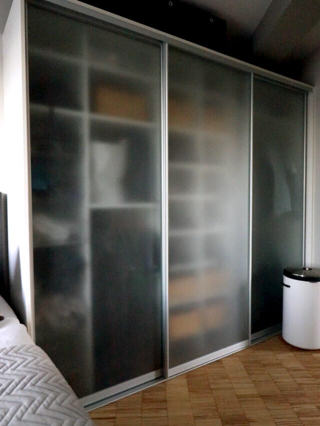 Elegant Elfa wardrobe with frosted glass sliding doors in modern bedroom